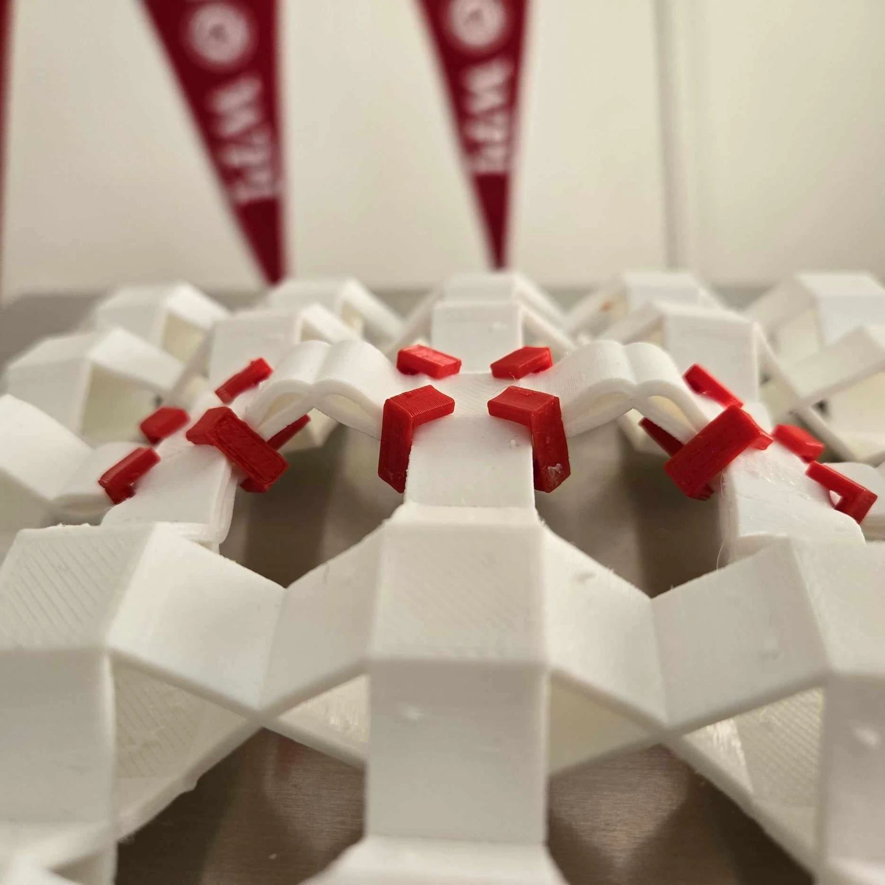 Close view of red retaining pins in a compliant Sarrus surface