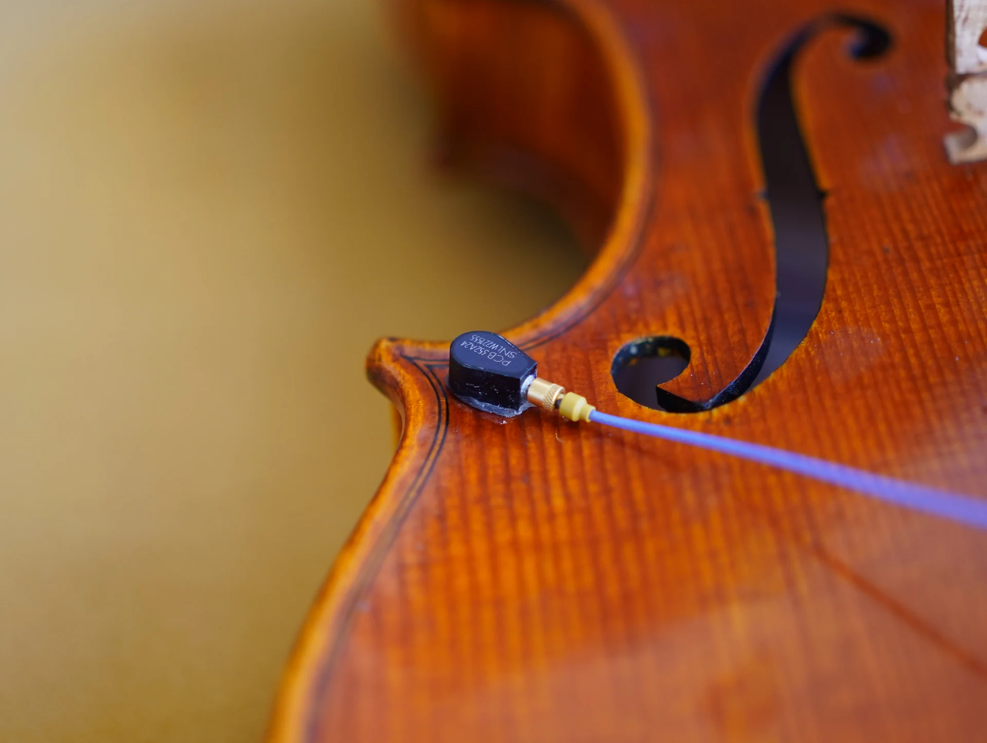 An accelerometer attached to the violin body for vibration measurements.